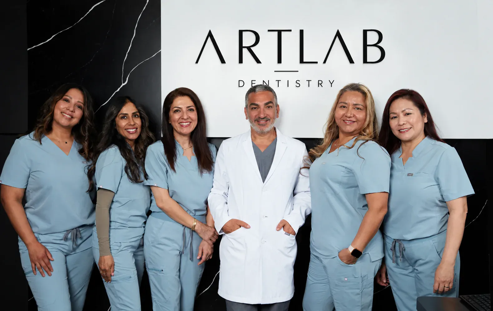 The ArtLab team in front of the new wordmark on the practice wall.